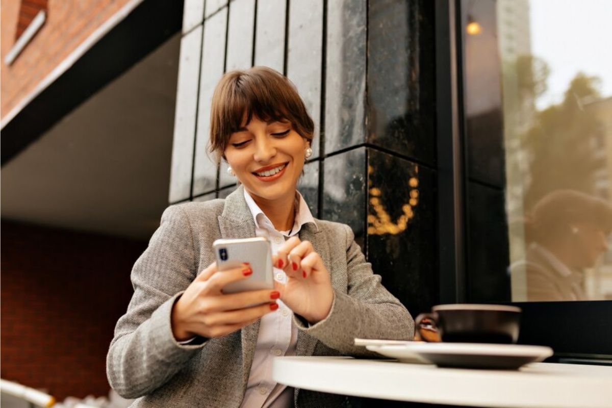 Uma mulher está mexendo no seu smartphone vendo Como Fazer um Currículo pelo Celular