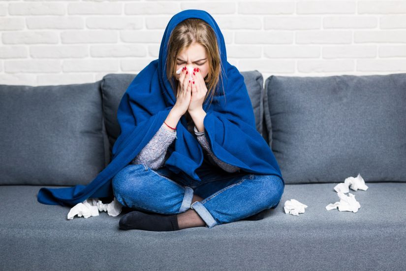 Mulher com uma gripe forte em cima do sofá.