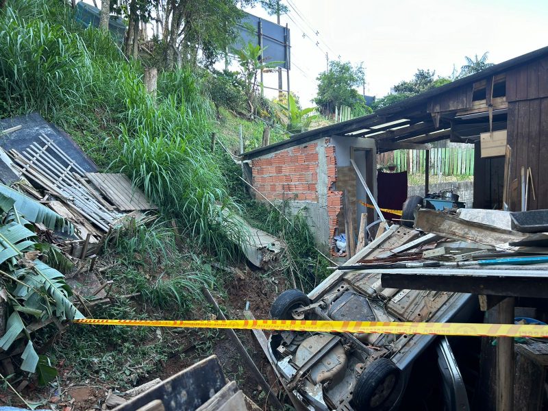 Imagem mostra carro sobre as casas em Itajaí