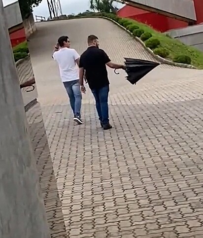 Douglas caminhando pelo pátio da empresa com um guarda-chuva na mão.