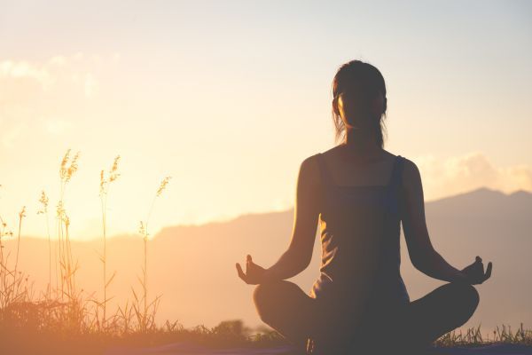 Silhueta de uma mulher fazendo yoga.