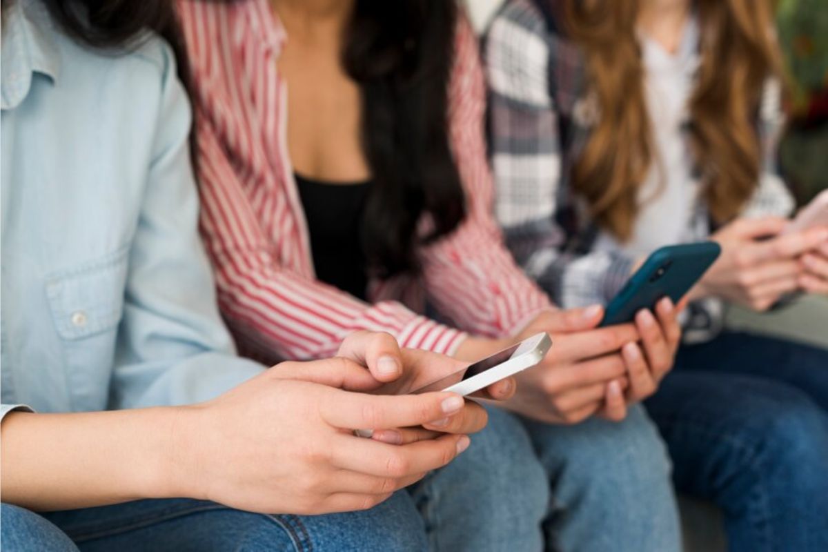 Três mulheres sentadas escolhendo um Papel de Parede Feminino para Celular