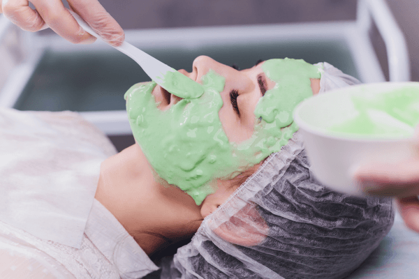 Foto de uma mulher com o rosto coberto por uma máscara facial gelatinosa.