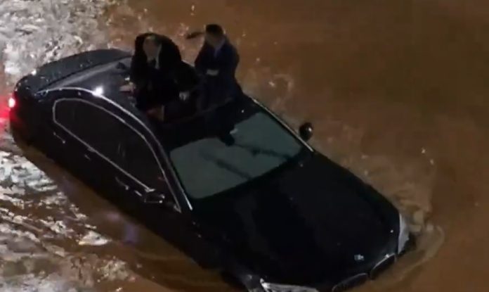 Pessoas sobem no teto de carro em alagamento no Anhangabaú